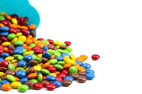 Rainbow Colored Candy Coated Chocolate Buttons in a Fun Blue Bowl Isolated on Foto stock