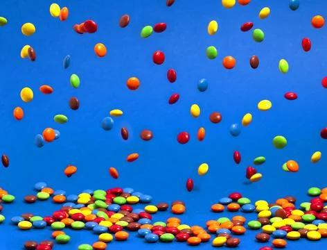 Rainbow Colored Candy Coated Chocolate Buttons Falling into a Pile Stock Photos