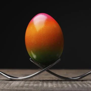 Rainbow colored Easter egg with two forks on a rustic wooden table 스톡 사진