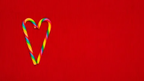 Rainbow colored heart shaped candy on a red cloth background, with copy space Stock Photos