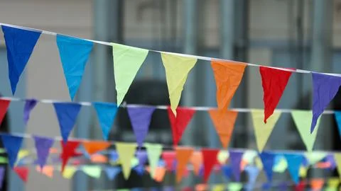 Rainbow-colored triangular flags hang in rows Stock Photos