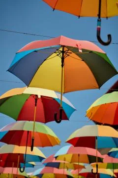 Rainbow colored umbrellas hanging in the sky. Summer travel. LGBT pride Stock Photos