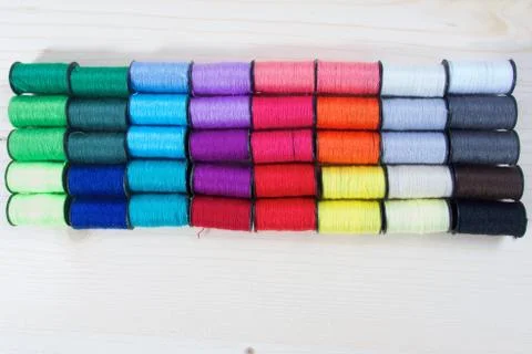 Rainbow of colourful thread spools on the table Stock Photos