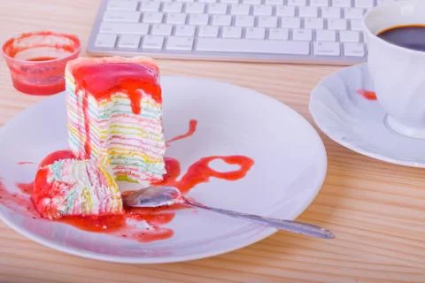 Rainbow crape cake with coffee on office table break time Stock Photos