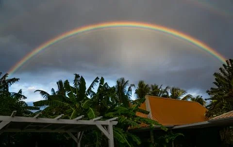 Rainbow on a dramatic overcast sky over a rooftop and patio Stock Photos