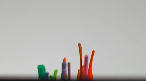 Rainbow droplets of paint splash up in slow motion, isolated on white Stock Footage 63905161