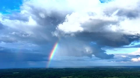 Rainbow Emerging After Rain Beneath Dynamic Clouds Over a Scenic Landscape Stock Footage 341210100