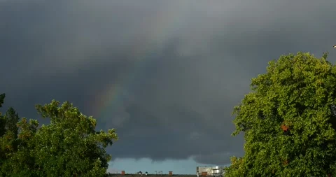 Rainbow Emerging Through Dark Rain Clouds Above Green Trees Video stock 337329959