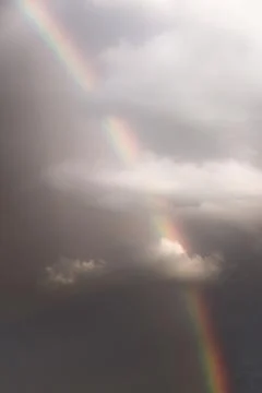 Rainbow emerging through dramatic clouds. Vertical orientation 스톡 사진