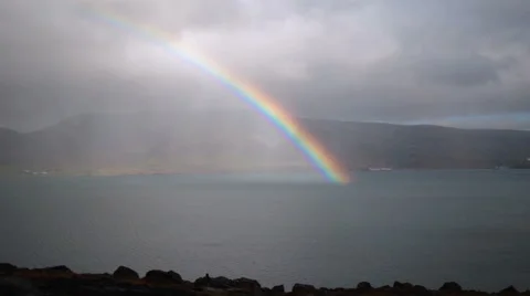 Rainbow ending in fjord water Hvalfjordur Iceland Stock Footage