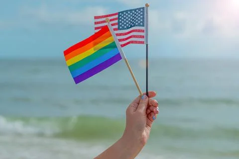 Rainbow Flag and American Flag. Woman hand holding the rainbow colors flag Stock Photos