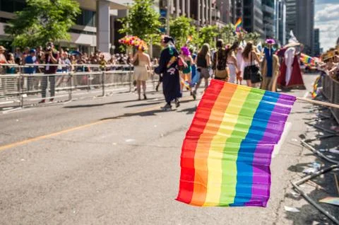 Rainbow flag floating in front of blurred Toronto gay pride participants Stock Photos