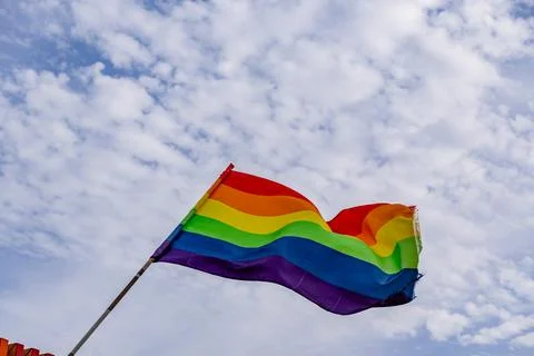 A rainbow flag is flying in the sky on a cloudy day Foto stock