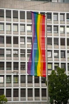 Rainbow flag in front of the windows of a large building Stock Photos