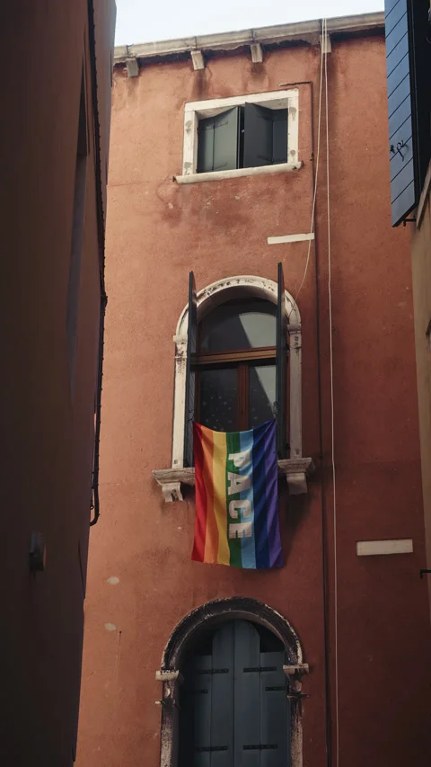 Rainbow flag with PACE word hangs on arched window of old Venetian building Stock Footage 320106348