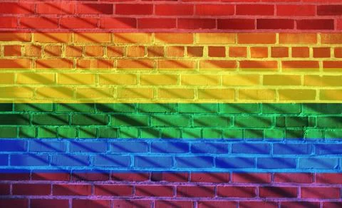 Rainbow flag projected on a sunny brick wall background Illustrazione stock