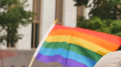 Rainbow flag waving with building and trees in background gay rights slow motion Stock Footage 51509603