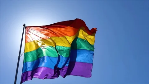 Rainbow flag waving at wind in the blue sky Stock Footage 122149473