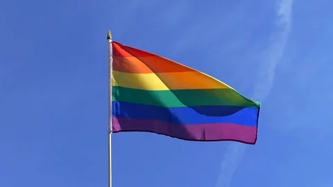 The Rainbow flag waving in the wind in the blue sky Stock Footage 282432936