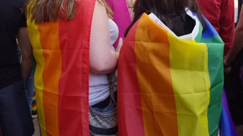 Rainbow flags are worn as capes in support at a Toronto pride parade - slow Stock Footage 124344573