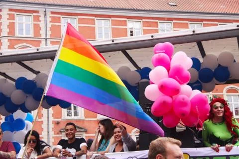 Rainbow flags in front of trolley with people and balloons at gay Pride Parade Stock Photos