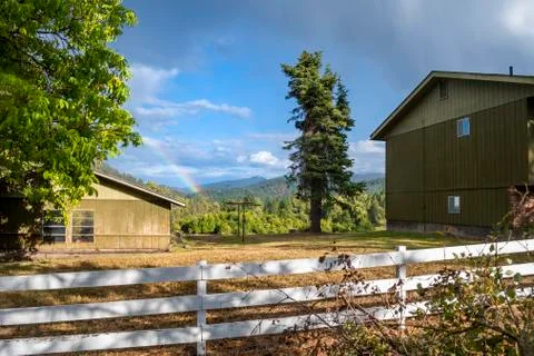 A rainbow forms above a ranch in rural America Stock Photos