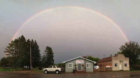 Rainbow (full) over over a couple small buildings Stock Footage 266327851