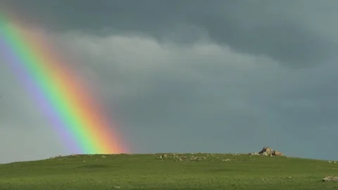 Rainbow glows over a green hillside - Prismatic Colors and Atmospheric Clearing Video stock 339718210