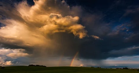 The rainbow glows in the sunlight against the background of dark clouds. Shadows Stock Footage 108005702