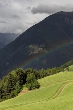Rainbow going over a mountain and a green hill Stock Photos