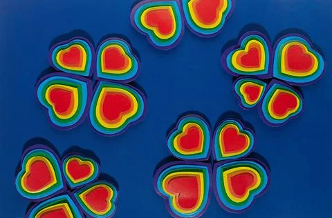 Rainbow hearts in flower shape pattern on dark blue background, top view. Stock Photos
