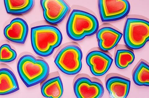 Rainbow hearts pattern on pastel pink background, top view. Stock Photos