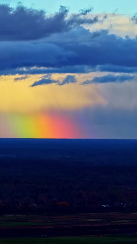 Rainbow at horizon and dramatic stormy sky with dark clouds at sunset in Latvia Stock Footage 336238692