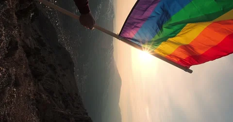 Rainbow LGBTQ flag. Waving rainbow flag in man's hands against stunning sunset Stock Footage 242827081