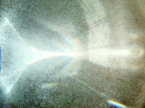 Rainbow light spectral reflection on scratched dark surface from water jug Foto stock