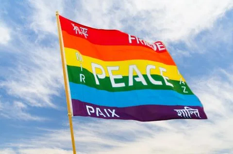 Rainbow multiolored peace flag wind flying against blue sky Stock Photos