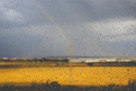 Rainbow outside window rainy day Weather forecast Raindrops on window surface Foto stock