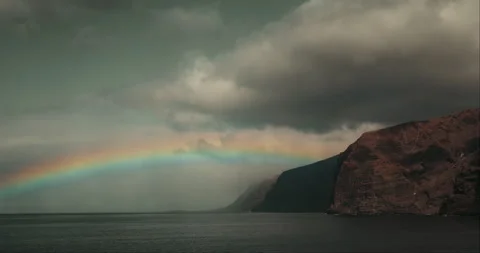 Rainbow Over Calm Ocean Waters and Steep Volcanic Cliffs in Tenerife Stock Footage 341348865