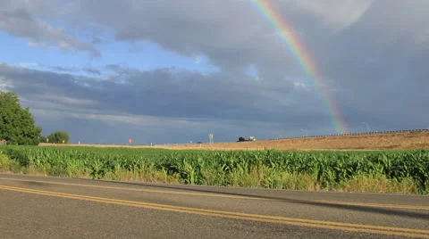 Rainbow over crops and road Stock Footage 56779055