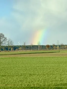 Rainbow Over Green Fields and Wind Turbines Foto stock