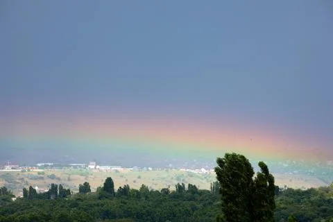 Rainbow over green trees Stock Photos
