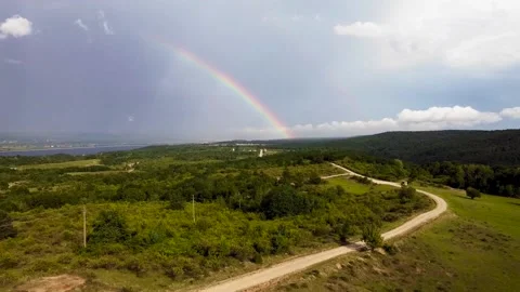 Rainbow over the hills after a rainy day aerial footage Stock Footage