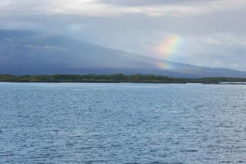 Rainbow over Isabela with shield volcano. Stock Photos