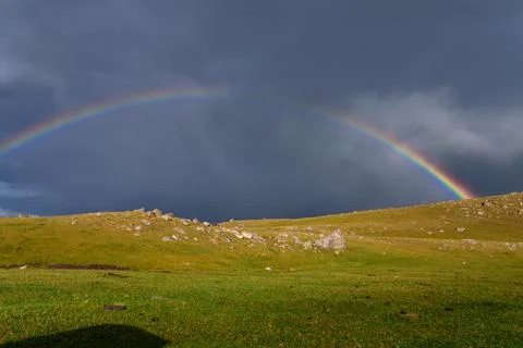 Rainbow over open field after rainstorm with dramatic sky Stock Photos