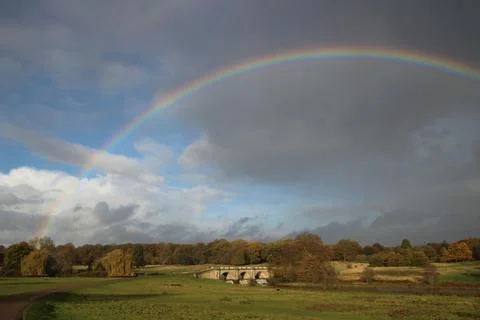 Rainbow over trees and fields. Stock Photos