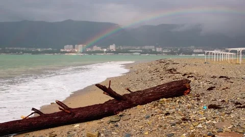 A rainbow over a winter pebble beach after a storm. On the front beach there is Stock Footage 256462030