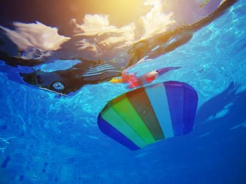 Rainbow pattern styrofoam swimming board floating in poolside water Foto stock