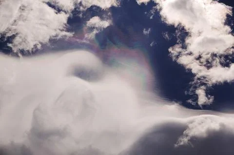 Rainbow patterns on ice crystals in high cloud above switzerland Stock Photos