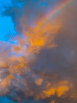 Rainbow Piercing Through Orange and Blue Sunset Clouds, Dramatic Sky Stock Photos