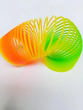 Rainbow plastic coil spring toy on white background Stock Photos